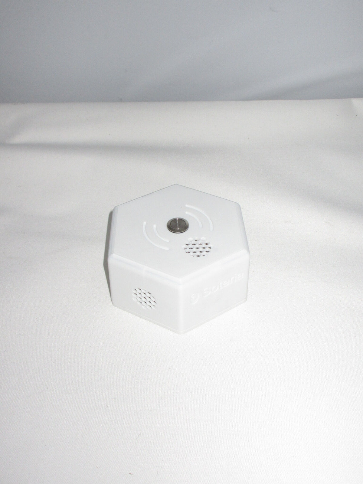 Close-up of Soteria Sense showing the top button, speaker grille and side sensor vents